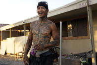 Meg Ledbetter smiles in front of the house he rents in Salton City, Calif., Wednesday, July 14, 2021. Ledbetter moved to Salton City from Riverside, Calif., five years ago after a stint in prison, to try to start a new life with his partner and their children. The community on the shore of the Salton Sea, California's largest but rapidly shrinking lake, has been through decades of economic stagnation. Now, it's at the forefront of efforts to make the U.S. a major global producer of lithium, the ultralight metal used in rechargeable batteries. (AP Photo/Marcio Jose Sanchez)