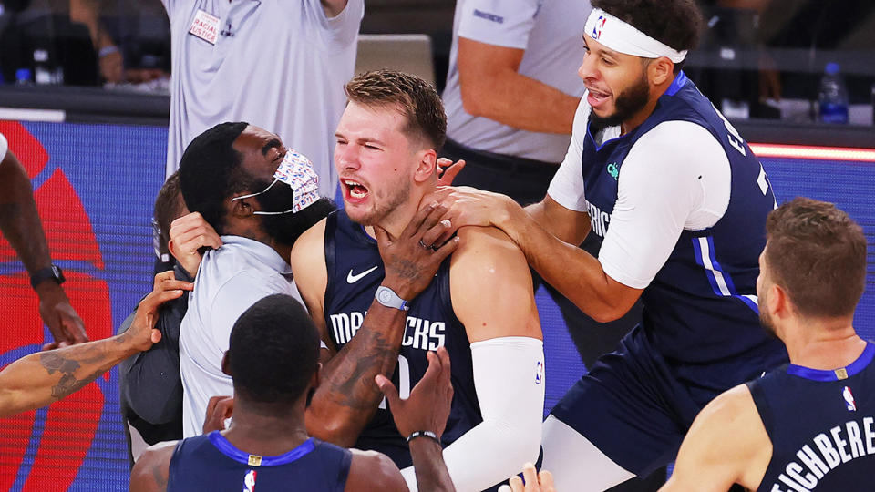 The Dallas Mavericks are pictured celebrating with point guard Luka Doncic after he hit a game-winning three-pointer in overtime against the LA Clippers.