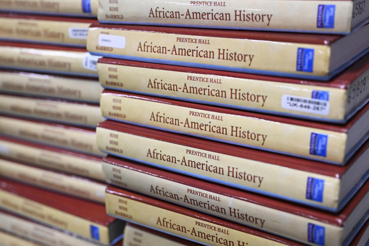 Books are piled up in a high school classroom for students taking AP African American studies.