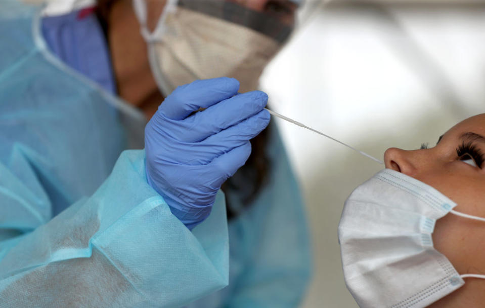 A nurse practitioner administers a COVID-19 nasal swab test at a Massachusetts high school. Experts say quicker, less expensive, less invasive saliva tests could help schools test students more often. (The Boston Globe / Getty Images)