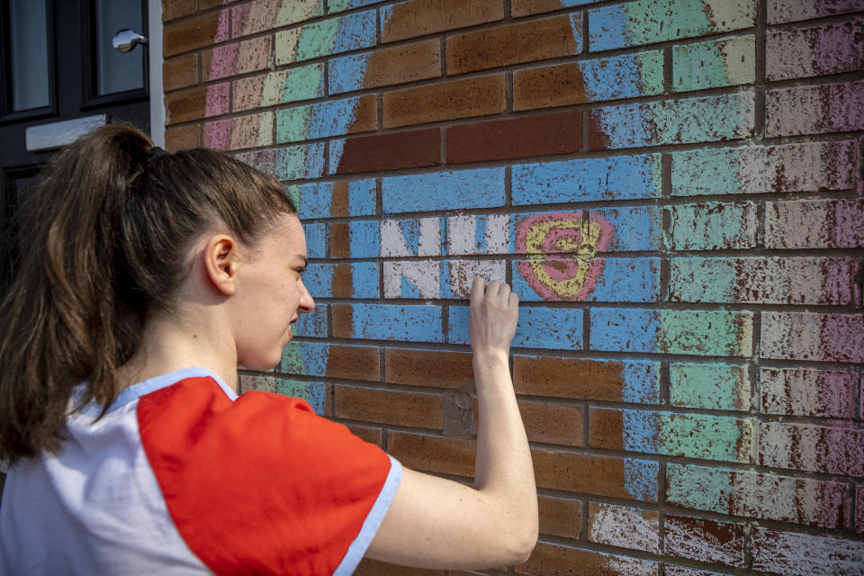 A teenager draws a rainbow and an NHS logo on the wall of her house in Liverpool in support of the NHS as the UK continues in lockdown to help curb the spread of the coronavirus.