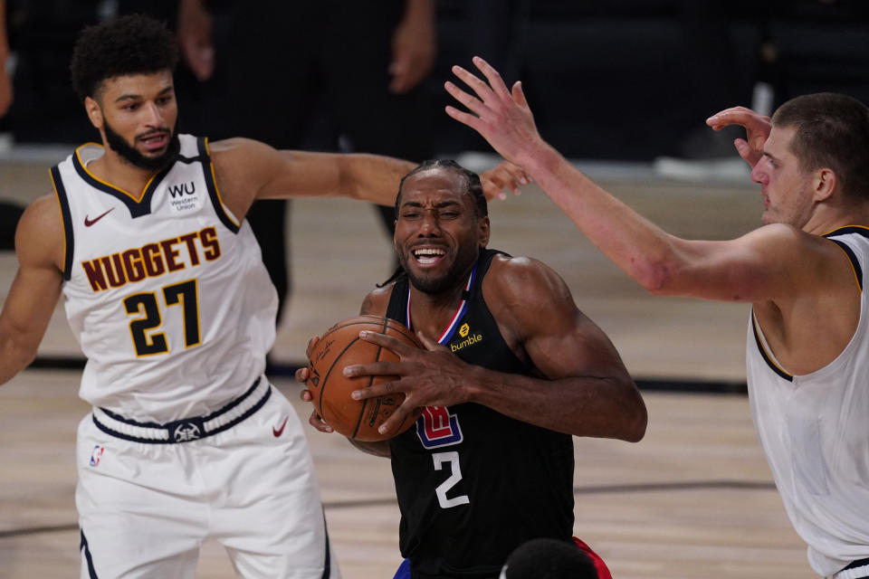 Kawhi Leonard, de los Clippers de Los Ángeles, avanza entre Jamal Murray (27) y Nikola Jokic, de los Nuggets de Denver, en el partido de playoffs disputado el jueves 3 de septiembre de 2020, en Lake Buena Vista, Florida (AP Foto/Mark J. Terrill)