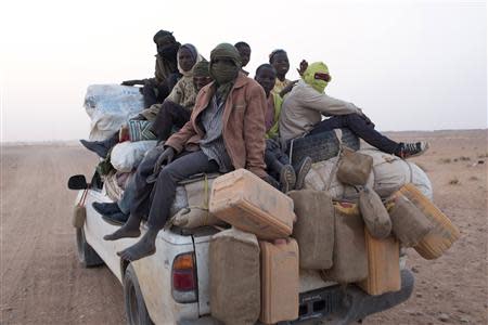 Nigerien migrants sit on a Toyota pickup truck as they return from Libya, in Agadez March 14, 2014. Picture taken March 14, 2014. REUTERS/Joe Penney