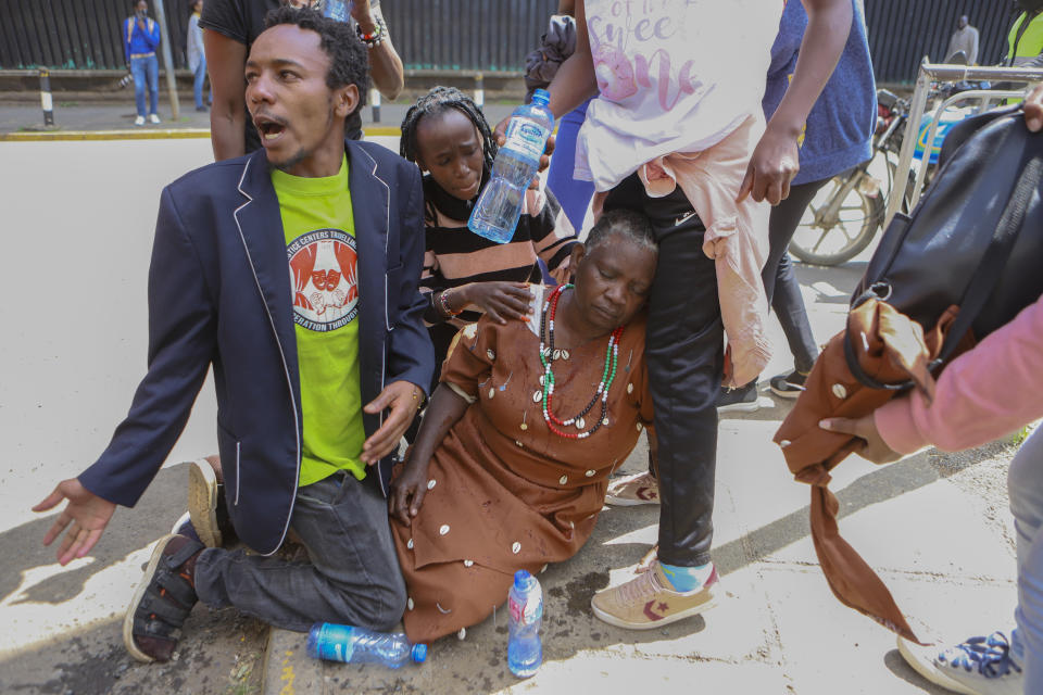 A woman suffering from tear gas inhalation sits on the ground during a protest against proposed tax hikes in a finance bill that is due to be tabled in parliament in Nairobi, Kenya, Tuesday, June 18, 2024. Civil society groups say that despite the dozens of arrests, demonstrations and a planned sit-down outside the parliament buildings will continue. (AP Photo/Andrew Kasuku)