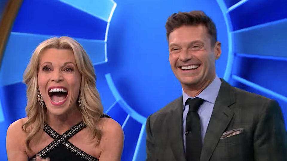     Vanna White and Ryan Seacrest smiling big on Wheel of Fortune. 