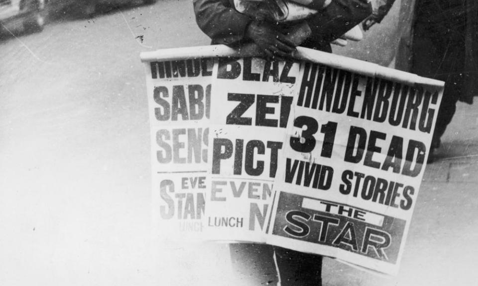 A London news vendor, carries posters promoting coverage of the Hindenburg disaster in local newspapers in London.