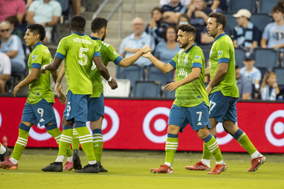 Seattle Sounders midfielder Cristian Roldan celebrates with teammates after scoring during the first half of an MLS soccer match against Sporting Kansas City, Sunday, Sept. 26, 2021, in Kansas City, Kan. (AP Photo/Nick Tre. Smith)