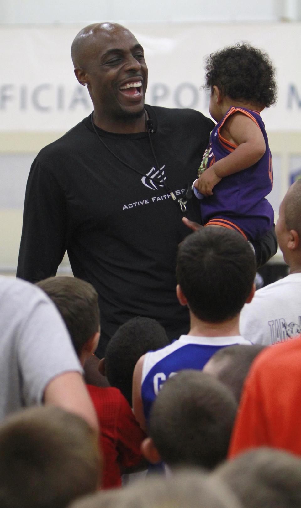Phoenix Suns basketball player Anthony Tolliver holds his son Isaiah, 1, as he talks to a group of kids during his basketball camp at The Courts on Tuesday, July 22, 2014.