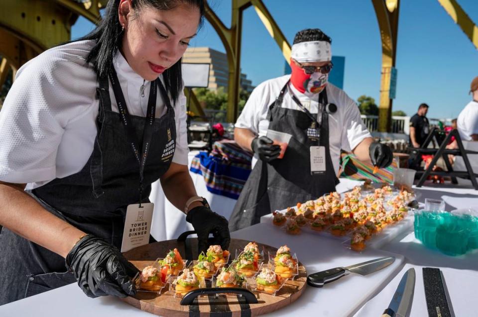 Marlene Zapata, left, and Jeremy Hidalgo, from Chicka Peruvian Kitchen & Cafe, prepare Cause Peruana, whipped potatoes with chili and lime, juice, avocado, mousse, and trout tartare, for the Tower Bridge Dinner on the Tower Bridge between Sacramento and West Sacramento on Sunday.