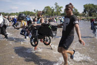Central American migrants carry a baby stroller across the Suchiate River from Guatemala to Mexico, near Ciudad Hidalgo, Mexico, Monday, Jan. 20, 2020. More than a thousand Central American migrants hoping to reach United States marooned in Guatemala are walking en masse across a river leading to Mexico in an attempt to convince authorities there to allow them passage through the country. (AP Photo/Santiago Billy)