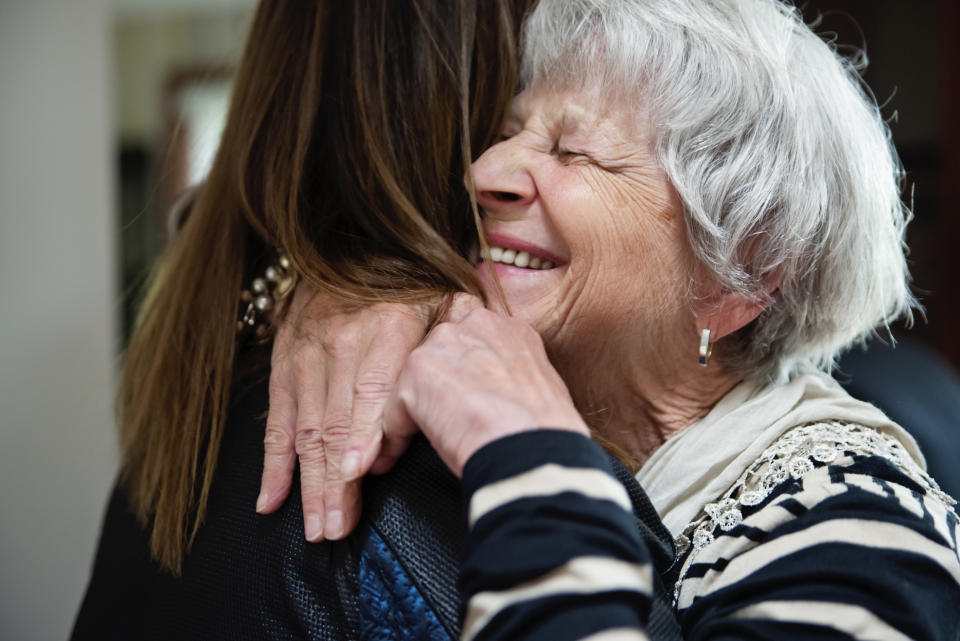 Women of all generations, shape and sizes partying, celebrating life and the birthday of one of them. They are family and friends from 20 to 75 year's old. Here mature grand-daughter hugging grandmother. Horizontal indoors waist up shot.