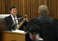 Forensic investigator Johannes Vermeulen, left, holding a cricket bat, is questioned during the trial of Oscar Pistorius in court in Pretoria, South Africa, Thursday March 13, 2014. Pistorius is charged with the shooting death of his girlfriend Reeva Steenkamp on Valentines Day in 2013. (AP Photo/Themba Hadebe, Pool)