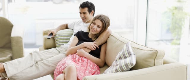 Couple sitting on sofa watching television