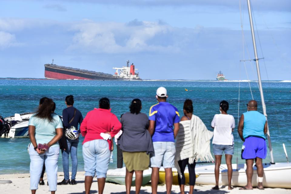 Locals look at the MV Wakashio bulk carrier that has run aground off the coast of Mauritius.