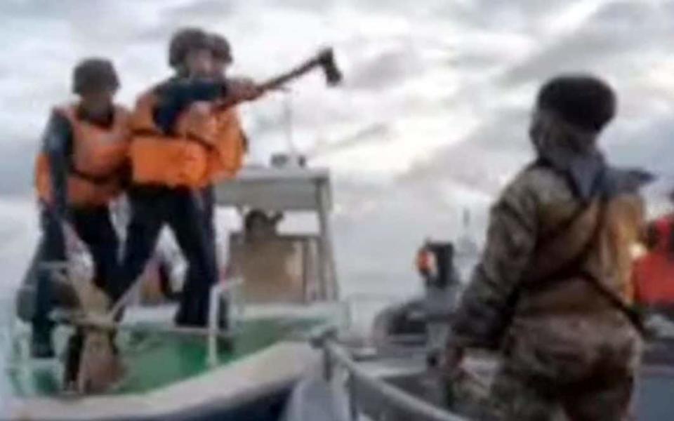 A Chinese coastguard holds an axe as they approach Philippine troops on Monday