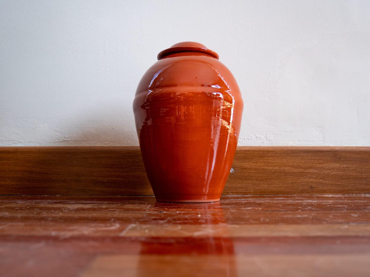 Orange Urn Leaning Against the White Wall