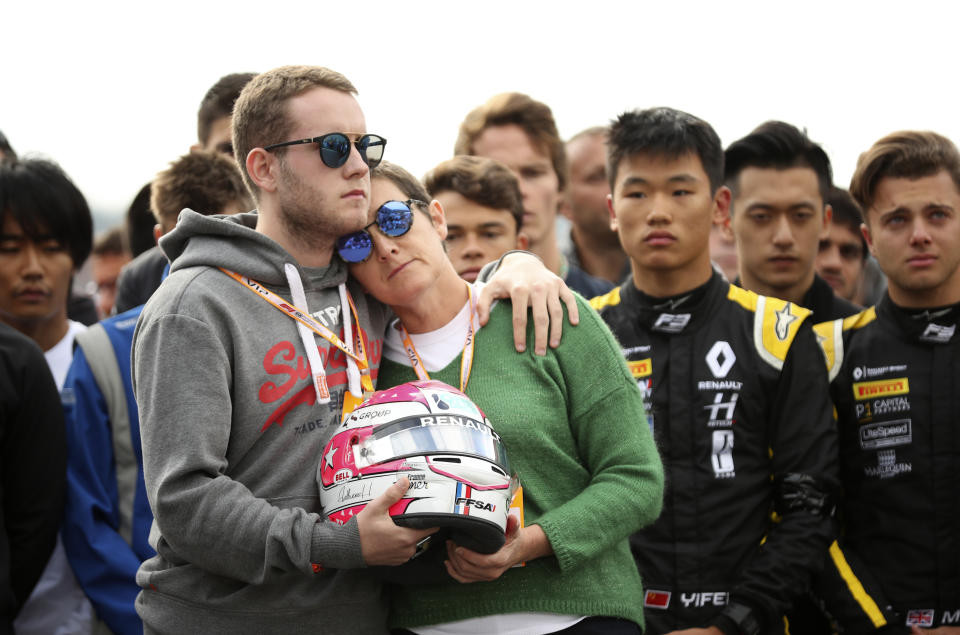 The mother and brother of Anthoine Hubert hold the helmet of Anthoine Hubert during a moment of silence at the Belgian Formula One Grand Prix circuit in Spa-Francorchamps, Belgium, Sunday, Sept. 1, 2019. The 22-year-old Hubert died following an estimated 160 mph (257 kph) collision on Lap 2 at the high-speed Spa-Francorchamps track, which earlier Saturday saw qualifying for Sunday's Formula One race. (AP Photo/Francisco Seco)