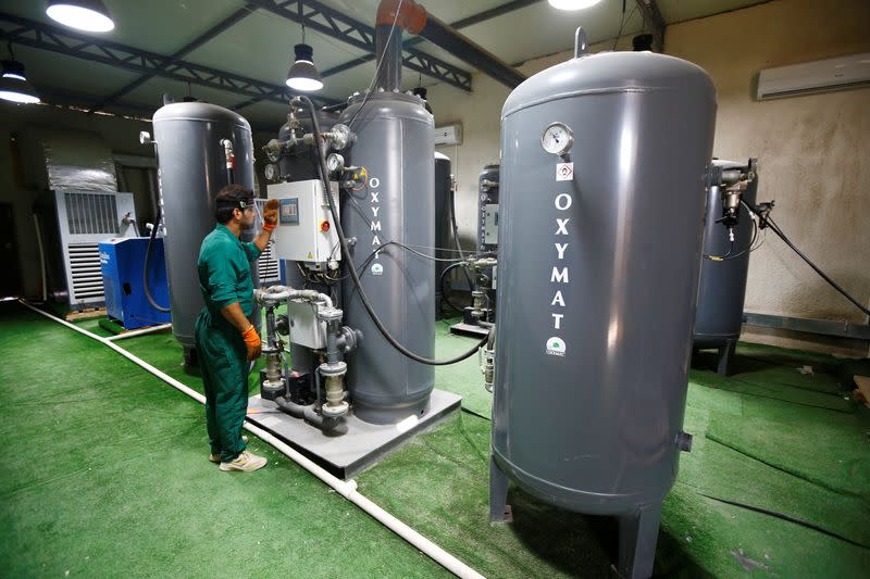 A worker wearing a protective face shield checks an oxygen level at a factory in the holy city of Kerbala