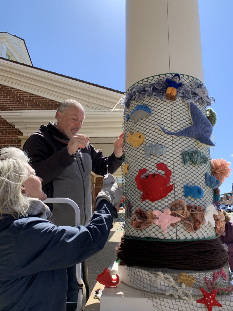 Volunteers attach sea creatures made out of yarn to a pillar for this year's Yarn Pop exhibit in Plymouth.