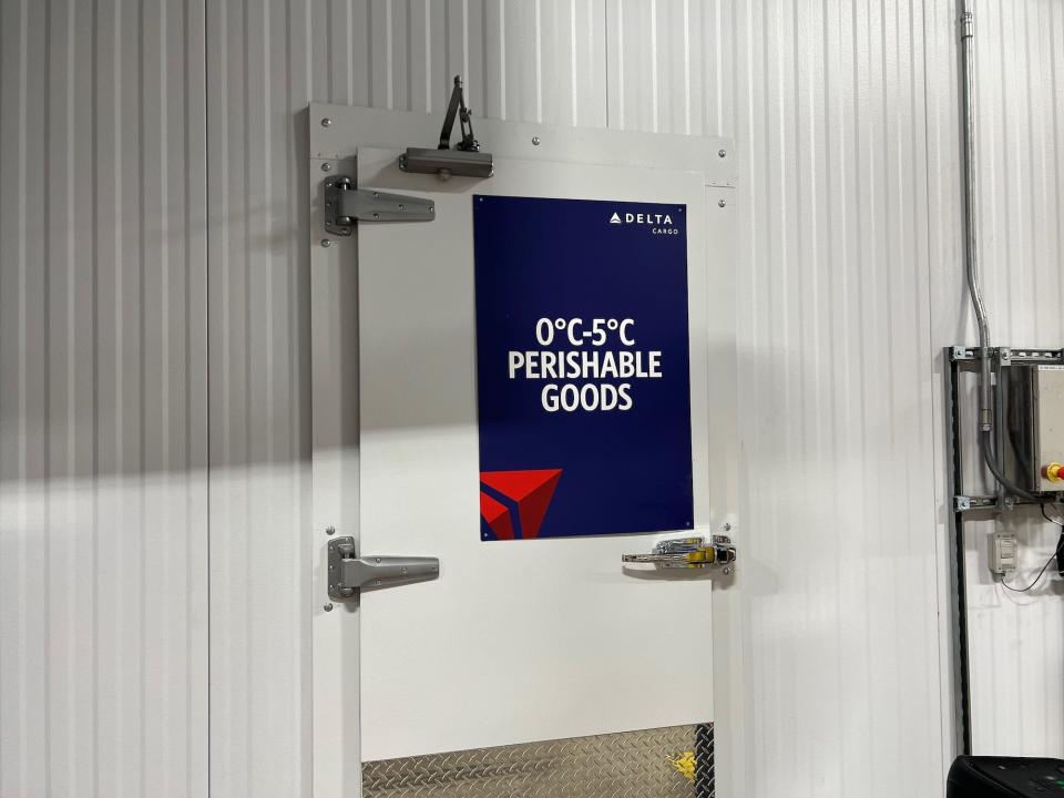 A door in the cooler with a sign for perishable goods and the temperature to store them at.