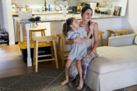 Lucy Reardon tears up as daughter Olivia Smith, 5, motions to comfort her as she describes being displaced by the 2023 wildfires, Monday, July 8, 2024, at their new apartment near Lahaina, Hawaii. Reardon says that after months of waiting for FEMA housing, a leasing program run by the Council for Native Hawaiian Advancement helped her family find stable housing quickly (AP Photo/Lindsey Wasson)