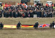 Relatives of the Germanwings Airbus A320 crash victims gather by a stele (R) during a wreath-laying and remembrance ceremony as rescuers hold flags of the passengers' nationalities, in the small village of Le Vernet, France, on March 26, 2015