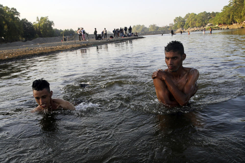 Honduran migrants bathe in the Suchiate River, which creates a natural border between Guatemala, left, and Mexico, near Tecun Uman, Guatemala, Wednesday, Jan. 22, 2020. The number of migrants stuck at the Guatemala-Mexico border continued to dwindle Wednesday as detentions and resignation ate away at what remained of the latest caravan. (AP Photo/Marco Ugarte)