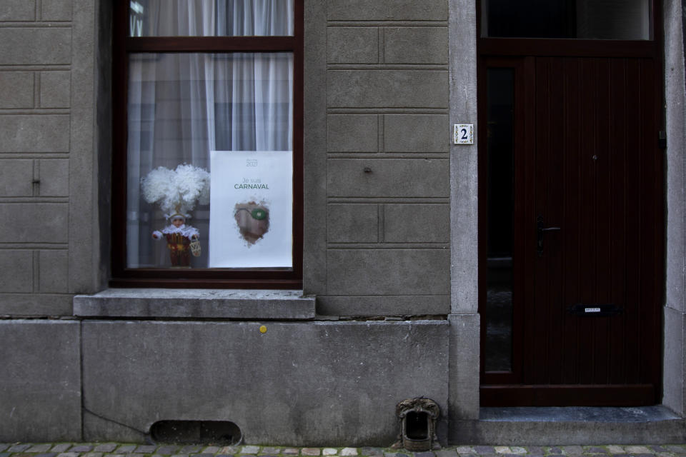 A poster which reads in French 'I am Carnival' hangs in solidarity in a window in Binche, Belgium, Thursday, Feb. 11, 2021. In normal life, the small town of Binche in southern Belgium would be bursting with excitement for the carnival festivities that have been labeled a 'Masterpiece of the Oral and Intangible Heritage of Humanity' by UNESCO, but in 2021 the COVID-19 regulations have forced the carnival to be cancelled. (AP Photo/Virginia Mayo)