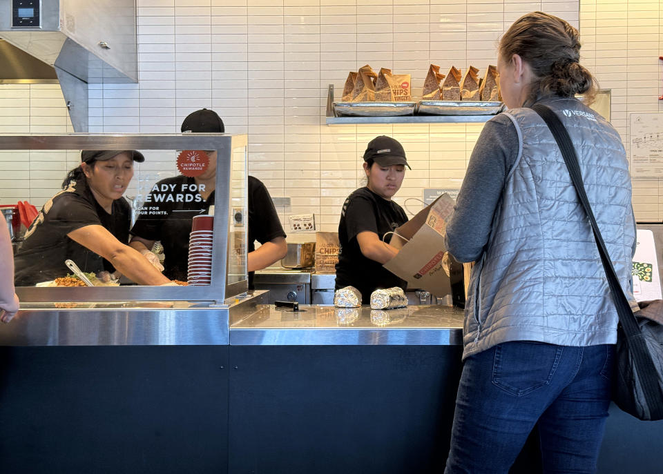 SAN RAFAEL, CALIFORNIA - APRIL 01: Workers help a customer at a Chipotle restaurant on April 01, 2024 in San Rafael, California. A new minimum wage law went into effect in California today that calls for fast food restaurants with at least 60 locations nationwide to pay employees a minimum of $20 per hour at their stores in California. (Photo by Justin Sullivan/Getty Images)