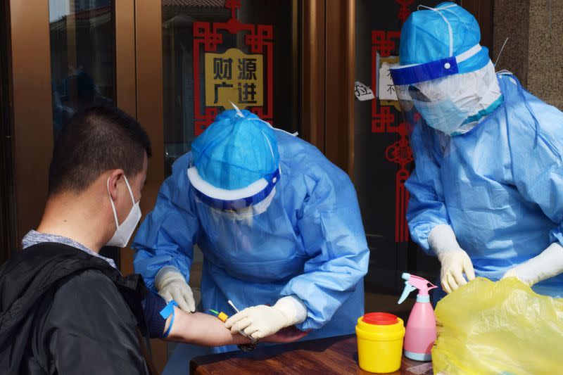 Worker draws blood from a man to conduct a test for antibodies against the coronavirus disease (COVID-19) in Suifenhe