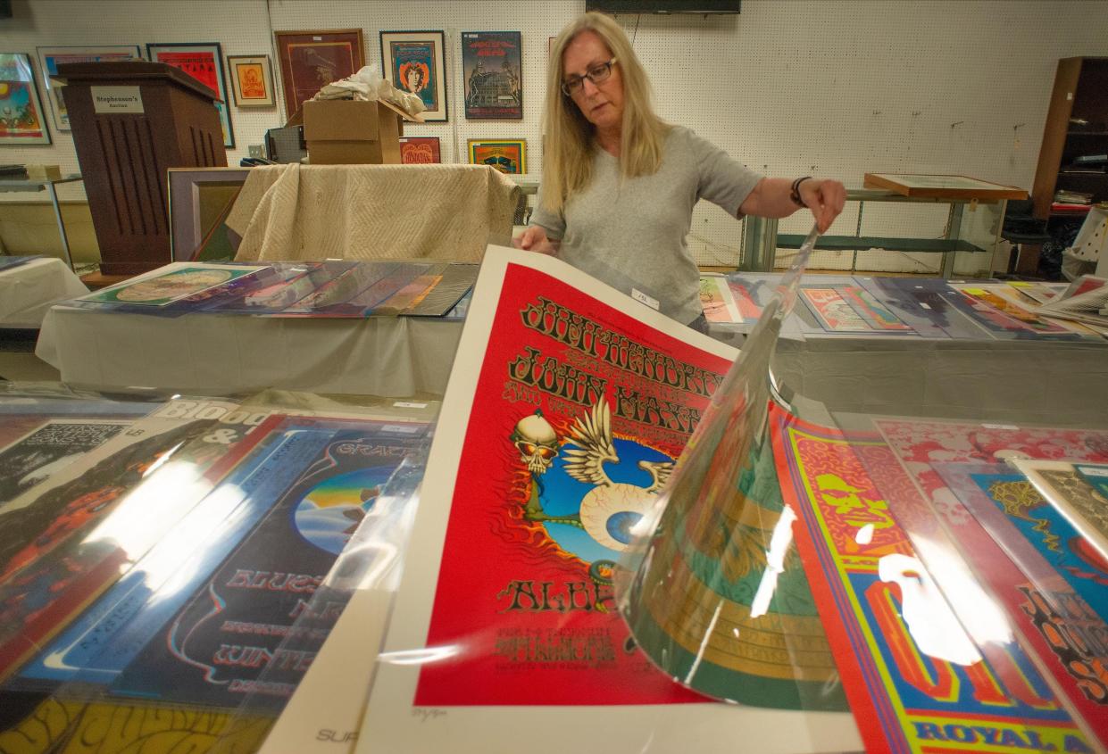 Cindy Stephenson looks through some of the 300-plus concert posters in the showroom while setting up for the auction of the Perry Pfeffer estate's collection of rock concert posters Tuesday at Stephenson's Auctioneers and Appraisers in Upper Southampton.