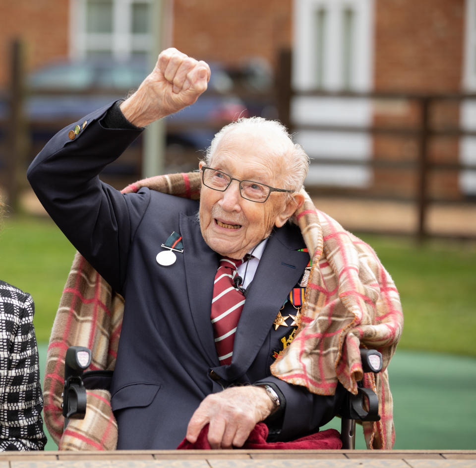 Captain Tom Moore as he waves to a Battle of Britain Memorial Flight flypast of a Spitfire and a Hurricane passing over his home as he celebrates his 100th birthday.