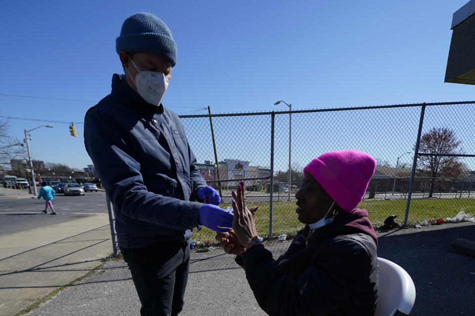 Nurse practitioner Bobby Harris, left, helps get a swab sample from Lisa McFadden while being treated near a Baltimore City Health Department RV, Monday, March 20, 2023, in Baltimore. The Baltimore City Health Department's harm reduction program uses the RV to address the opioid crisis, which includes expanding access to medication assisted treatment by deploying a team of medical staff to neighborhoods with high rates of substance abuse and offering buprenorphine prescriptions. (AP Photo/Julio Cortez)