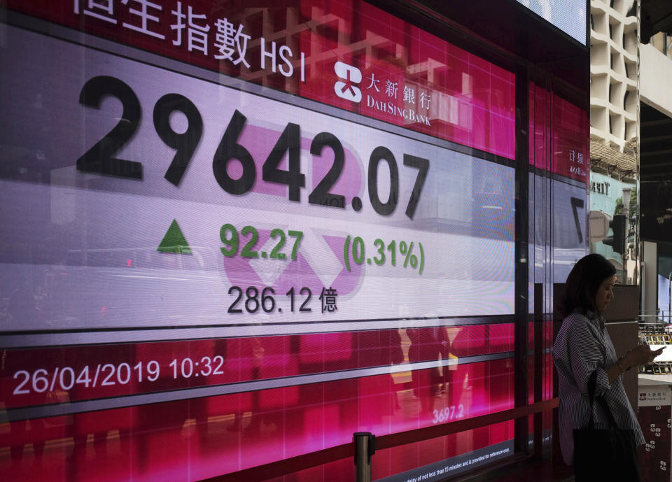 A woman stands next to a bank electronic board showing the Hong Kong share index at Hong Kong Stock Exchange Friday, April 26, 2019. Shares were mostly lower in Asia on Friday after an overnight decline on Wall Street spurred by disappointingly weak earnings reports from 3M and other industrial companies. (AP Photo/Vincent Yu)