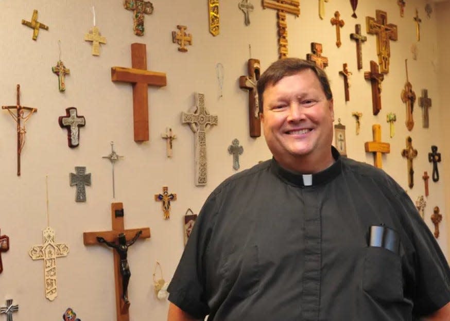 The Rev. Mike Ingram smiles beside a wall of crosses and crucifixes in this photo from 2011, shortly after arriving at St. Teresa of Avila Catholic Church in Grovetown. Ingram died April 2 at age 69.