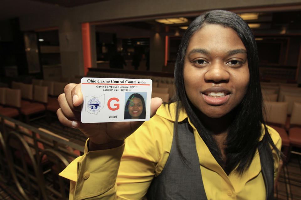 Taneshia Pitts, 28, holds up the first gaming employee license issued at the Horseshoe Casino in Cleveland Thursday, April 5, 2012. The commission has approved more than 1,100 licenses and is investigating more than 500 other applicants. The Cleveland casino opens during the week of May 14. Toledo’s will open two weeks later and casinos in Cincinnati and Columbus will open next year. (AP Photo/Tony Dejak)