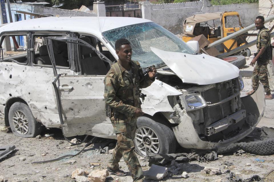 Somali soldiers walk near a vehicle, at the scene of a suicide car bomb attack in Mogadishu, Somalia, Monday, Jan. 2, 2017. A suicide bomber detonated an explosives-laden vehicle at a security checkpoint near Mogadishu's international airport Monday, killing at least three people, a Somali police officer said. (AP Photo/Farah Abdi Warsameh)