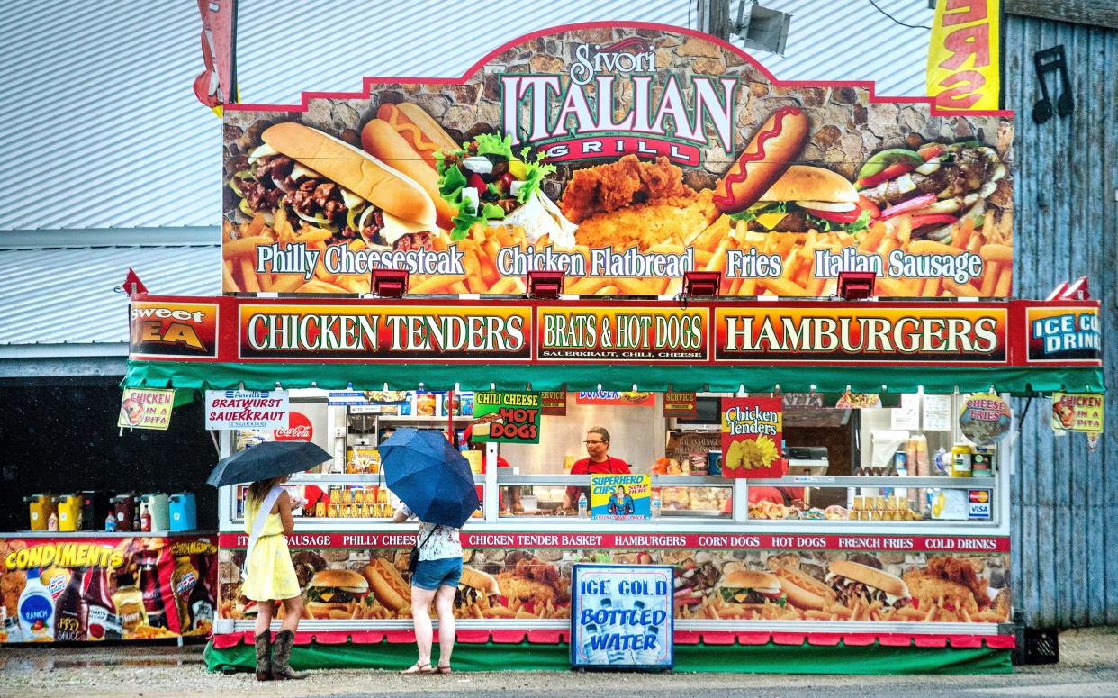 A pair of fairgoers belly up to a food vendor in a steady drizzle Wednesday, July 17, 2019 at the HOI Fair.