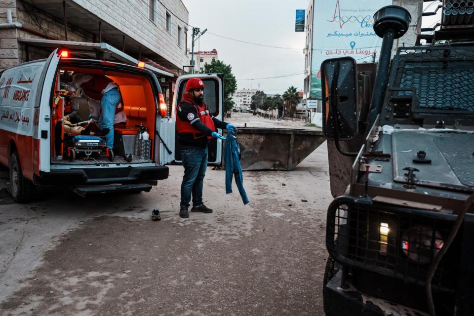 A paramedic is searched by Israeli soldiers.