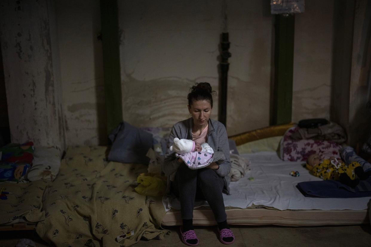 A woman holds her newborn baby inside a basement used as a bomb shelter at the Okhmadet children's hospital in central Kyiv, Ukraine, Monday, Feb. 28, 2022. Explosions and gunfire that have disrupted life since the invasion began last week appeared to subside around Kyiv overnight, as Ukrainian and Russian delegations met Monday on Ukraine’s border with Belarus. It's unclear what, if anything, those talks would yield. Terrified Ukrainian families huddled in shelters, basements or corridors, waiting to find out.