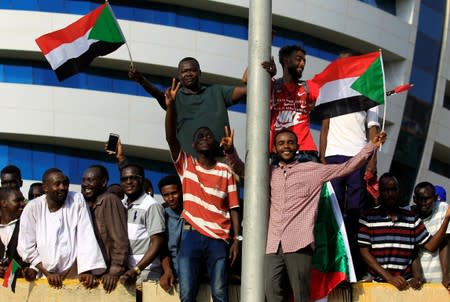 Civilians hold their national flag as they celebrate the signing of the Sudan's power sharing deal, in Khartoum