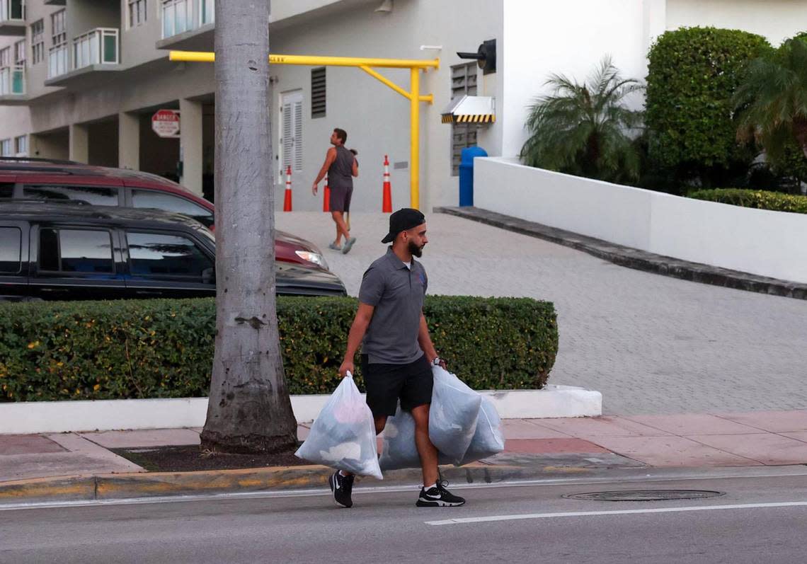 A resident crosses the street carrying bags outside the Port Royale condos at 6969 Collins Ave, Miami Beach, after everyone who lives there was told to evacuate by 7 p.m. due to structural concerns on Thursday, Oct. 27, 2022.