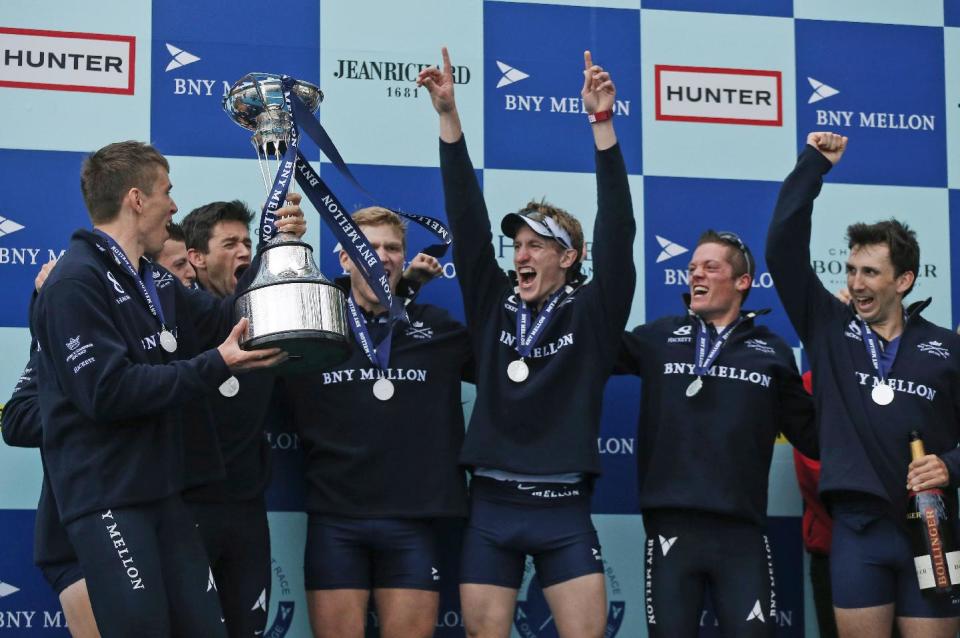 Members of the Oxford University's boat race crew celebrate with the trophy after their win against Cambridge University at the end of their 160th annual Boat Race on the River Thames, London, Sunday, April 6, 2014. The traditional boat race is a hotly contested point of honor between Oxford and Cambridge universities, and Cambridge still leads the series 81-78, with one tie. (AP Photo/Sang Tan)