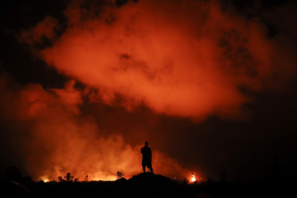 FILE - In this Friday, May 18, 2018 file photo, Peter Vance photographs lava erupting from the Kilauea volcano in the Leilani Estates subdivision near Pahoa, Hawaii, on May 18, 2018. A Cold War-era law in Hawaii that allows authorities to impose sweeping restrictions on press freedoms and electronic communications during a state of emergency could soon be repealed by lawmakers after concerns about its constitutionality and potential misuse in an era of increasing polarization. (AP Photo/Jae C. Hong, File)