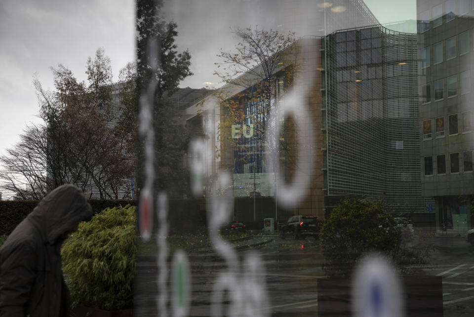 A man walks in the rain outside EU headquarters in Brussels, Thursday, Dec. 24, 2020. European Union and British negotiators worked through the night and into Christmas Eve in the hopes of putting the finishing touches on a trade deal that should avert a chaotic economic break between the two sides on New Year's Day. (AP Photo/Virginia Mayo)