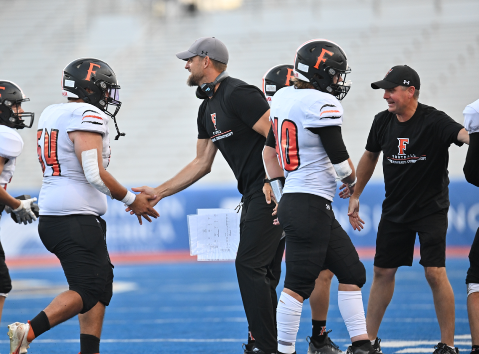 Former Carolina Panther Jordan Gross (in tan cap) congratulates one of the high school players he coaches during a game in Boise, Idaho. Gross, a member of the Carolina Panthers Hall of Honor as an offensive tackle, has returned to his hometown in Fruitland, Idaho, where he is now the head coach of the Fruitland Grizzlies.