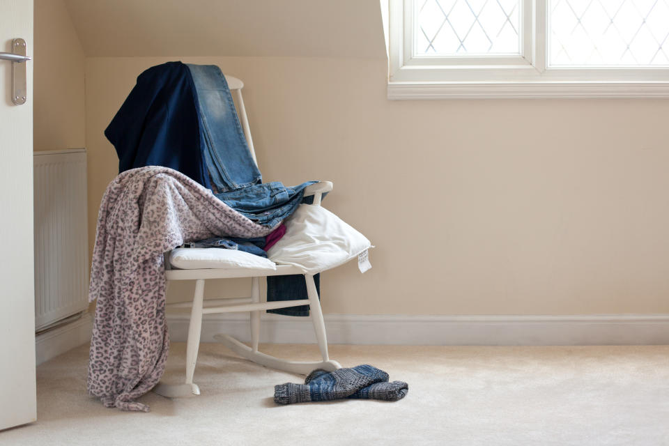 Ironing board with clothes draped over it and a pair of shoes on the floor, indicating a casual, disorganized space