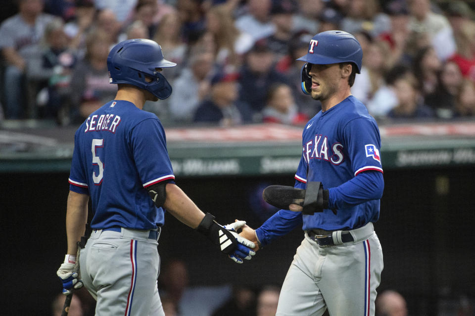 Texas Rangers' Corey Seager, left, congratulates Evan Carter, right, who scored on a double by Marcus Semien during the fifth inning of a baseball game against the Cleveland Guardians in Cleveland Saturday, Sept. 16, 2023. (AP Photo/Phil Long)