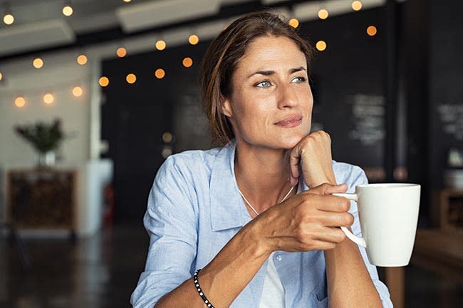 Mujer madura con una taza de café en actitud pensativa