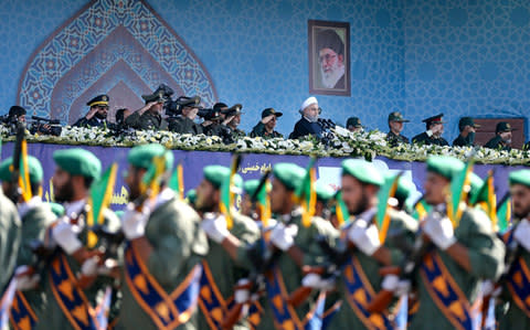 Iran's President Hassan Rouhani, top center, reviews army troops marching - Credit: AP Photo/Ebrahim Noroozi